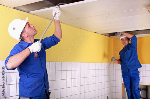 Photo: duo of electricians working indoors duo of electricians working indoors