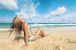 Young woman sitting on a sand of the tropical beach