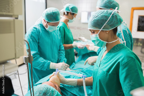 Photo: Nurse holding an oxygen mask on a patient undergoing an operatio Nurse holding an oxygen mask on a patient undergoing an operatio