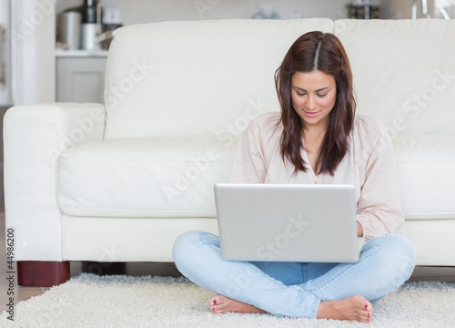 Photo: Woman sitting on the carpet with her laptop Woman sitting on the carpet with her laptop