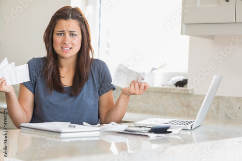 Photo: Woman looking troubled while holding bills Woman looking troubled while holding bills