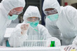 Photo: Chemist adding green liquid to test tubes with two other chemist Chemist adding green liquid to test tubes with two other chemist