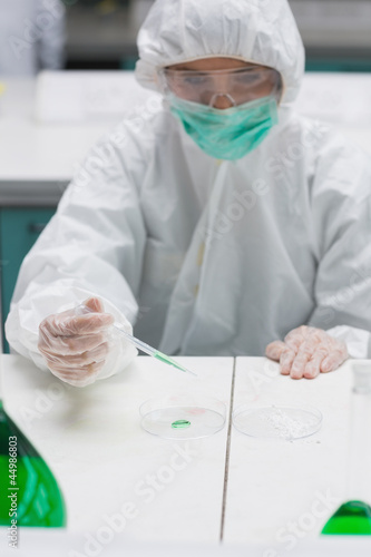 Photo: Woman in protective gear working with green liquid Woman in protective gear working with green liquid
