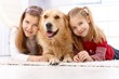 Happy girls with dog smiling at home