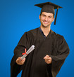 Young Man In Graduation Gown Holding Certificate