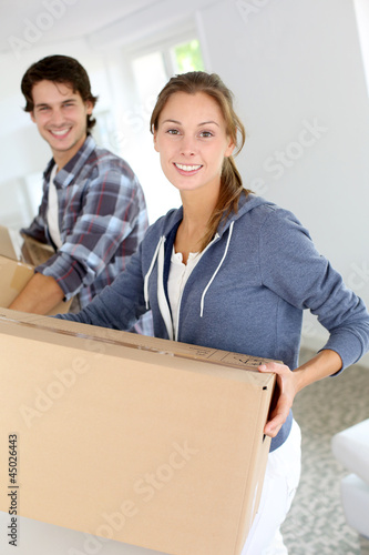 Photo: Smiling couple leaning on boxes in new home Smiling couple leaning on boxes in new home