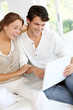 Happy young couple using laptop computer at home