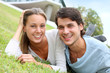Cheerful couple of lovers laying in garden