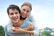 Man giving piggyback ride to girlfriend outside