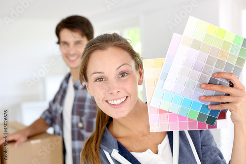 Foto: Smiling girl holding colour charts to decorate house Smiling girl holding colour charts to decorate house