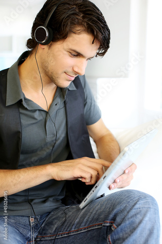 Photo: Handsome guy listening to music on internet with tablet Handsome guy listening to music on internet with tablet