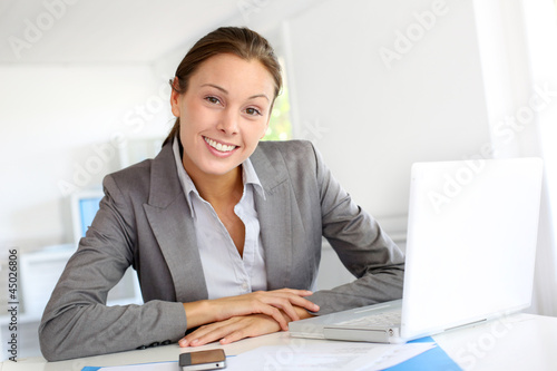 Photo: Smiling businesswoman sitting at her desk Smiling businesswoman sitting at her desk