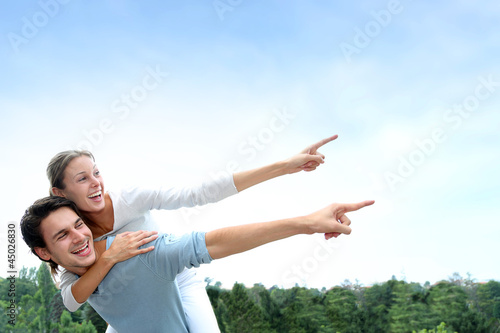Photo: Man giving piggyback ride to girlfriend outside Man giving piggyback ride to girlfriend outside