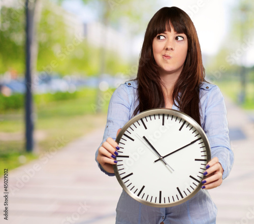 Photo: A Young Girl Holding A Clock And Making Face A Young Girl Holding A Clock And Making Face