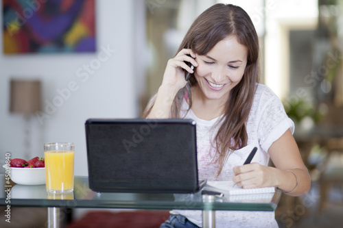 Photo: Happy woman working at home and talking to a customer Happy woman working at home and talking to a customer