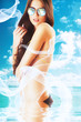 attractive brunette woman in white fabric on the beach in water