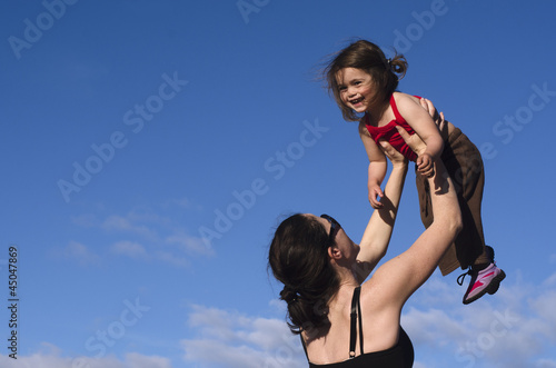 Photo: Mother holds her daughter up in the air Mother holds her daughter up in the air