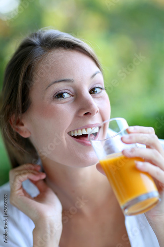 Photo: Closeup of woman drinking orange juice from glass Closeup of woman drinking orange juice from glass