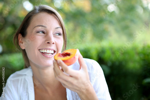 Photo: Smiling woman eating peach for breakfast Smiling woman eating peach for breakfast