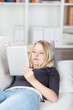 junge frau liegt auf dem sofa und liest am tablet