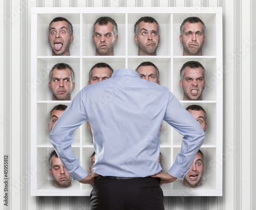 Photo: Young man choosing which face expression to wear Young man choosing which face expression to wear