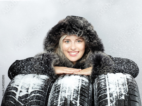 Photo: Pretty woman with winter coat behind snowy winter tyres Pretty woman with winter coat behind snowy winter tyres