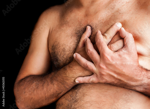 Photo: Shirtless man suffering a heart attack isolated on black Shirtless man suffering a heart attack isolated on black
