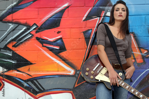 Photo: Woman with guitar in front of graffiti Woman with guitar in front of graffiti