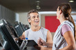 Happy Instructor Looking At Female Client Exercising On Treadmil