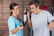 Instructor Assisting Man In Getting Down From Exercise Machine