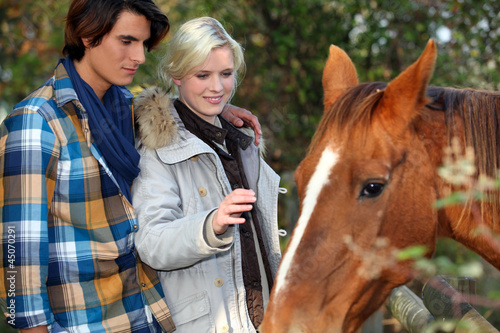 Photo: Young couple petting horse Young couple petting horse