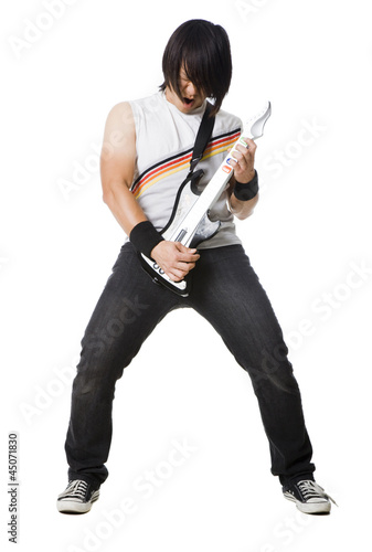 Photo: "Young man playing guitar video game and screaming, studio shot" "Young man playing guitar video game and screaming, studio shot"
