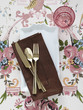 Plate with napkin and cutlery on floral tablecloth
