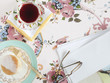 "Food and drink with glasses and paper, on floral tablecloth"