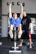 Instructor assisting man exercising in gym