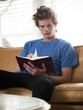"USA, Utah, Provo, young man reading book on sofa"