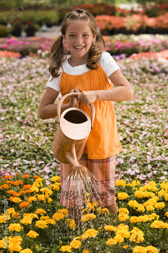 Photo: "USA, Utah, Salem, portrait of girl (8-9) watering flowers" "USA, Utah, Salem, portrait of girl (8-9) watering flowers"