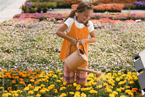 Photo: "USA, Utah, Salem, girl (8-9) watering flowers" "USA, Utah, Salem, girl (8-9) watering flowers"