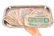 Hand holding tray of world monies, isolated on white