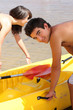 Young couple putting a canoe in the water
