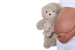 A pregnant woman holding a teddy bear.