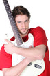 Young man hugging his guitar