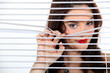 pretty woman behind blinds spying upon neighbours