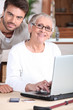Young man helping senior woman with a laptop computer