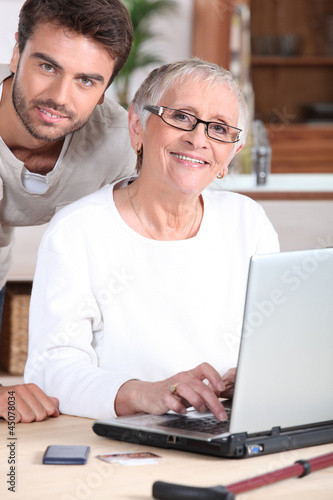 Photo: Young man helping senior woman with a laptop computer Young man helping senior woman with a laptop computer