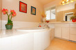 Bathroom with large round white tub and cabinets