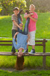 Teenage boys holding their girl friend upside down in the park