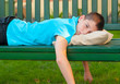 Sad lonely teenage boy lying on the bench
