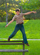 Happy teenage boy jumping from the bench in the park
