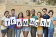 Photo: Group of young people holding teamwork sign Group of young people holding teamwork sign